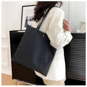 Detail shot of black tote bag featuring vertical pleated texture and long shoulder straps