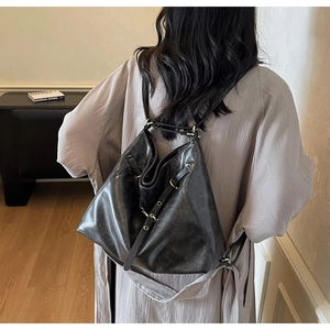 Close-up of a vintage black soft leather backpack with drawstring and metal buckles