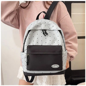 Detailed view of polka dot backpack featuring the front pocket and brand logo patch