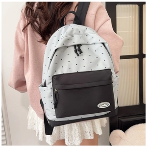 Detail of blue polka dot canvas backpack featuring a front zipper pocket and Lolo logo
