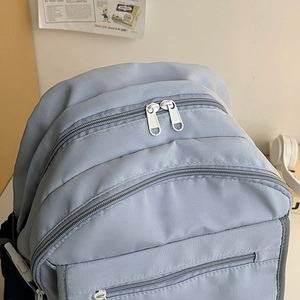 Top view of a light blue nylon school backpack featuring multiple zipper compartments
