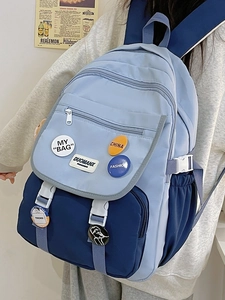 Detail of blue color-block backpack showing multiple pockets and decorative badges