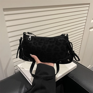 Black leopard print shoulder bag with silver hardware and bow details shown by hand