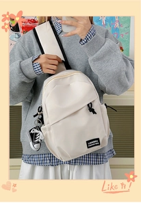 Detailed close-up of beige nylon crossbody bag with mini sneaker charm and logo patch