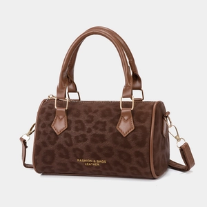 Macro shot of brown leopard print texture on velvet bag with gold zipper and leather trim