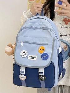 Detail of color-block nylon backpack with decorative badges and plush pendant accessory