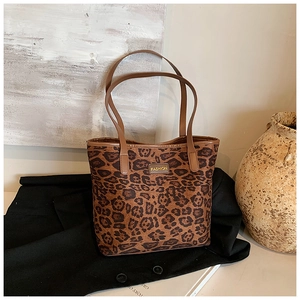 Detailed close-up of leopard print tote bag with brown handles and fashion label
