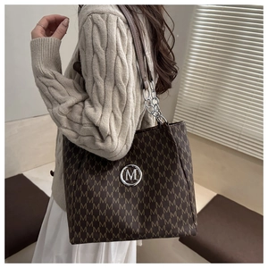 Detailed side view of large tote bag with M-pattern print and chain shoulder strap