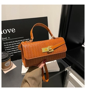 Detail of caramel woven texture hand bag with elegant golden metallic twist lock closure