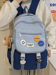 Detail of color-block school backpack with cute bear pendant and decorative badges