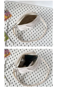 Detail showing internal storage of white PU crossbody bag with dual zipper compartments