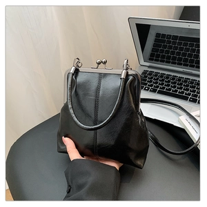 Détail du fermoir kiss-lock argenté et de la poignée sur un sac en cuir noir ciré