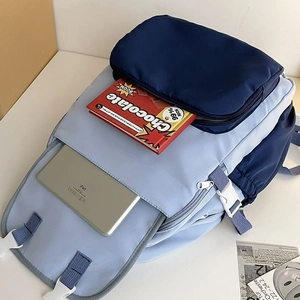 Detail showing spacious internal storage with iPad and books in two-tone blue backpack