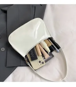 Spacious interior of beige patent leather shoulder bag showing storage capacity