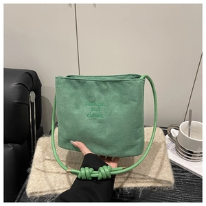 Gros plan du sac en daim vert avec bandoulière nouée et embossage fashion and classic