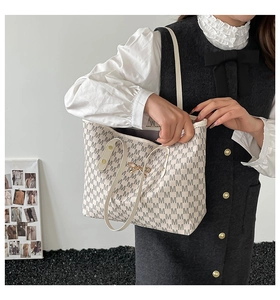 Vue latérale d'un sac cabas à monogramme avec nœud doré et bandoulière pour femme