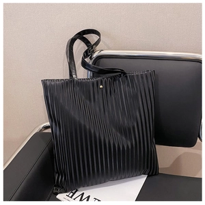 Detail view of the black pleated fabric texture and gold button on the tote bag