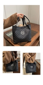 Detail of black tote bag with M-pattern print, leather strap, and silver chain accent