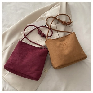 Détail de sacs en daim bordeaux et camel avec bandoulières nouées et texte gaufré élégant