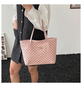 Détail du sac cabas rose avec imprimé M et nœud doré porté par un mannequin femme