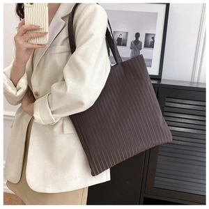 Macro detail of brown pleated tote bag showing vertical accordion texture and shoulder strap