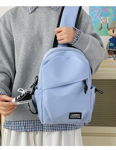 Detailed close-up of light blue nylon crossbody bag with zipper and logo label