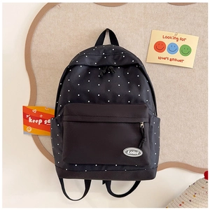 Detailed close-up of a black polka dot backpack with a durable front zipper pocket