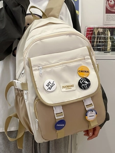 Detail of color-block school backpack with decorative fashion badges and multi-pocket design