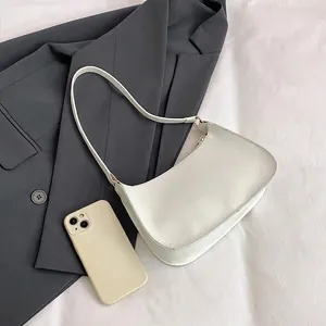 Minimalist white baguette shoulder bag in faux leather on fabric with a grey blazer