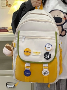 Detail of color-block school backpack with decorative badges and plush toy pendant