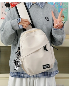 Cream crossbody bag detail with LIANGKU label and mini sneaker charm on wide strap