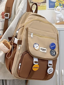 Close-up of contrast color school backpack with multiple pockets and cute plush pendant