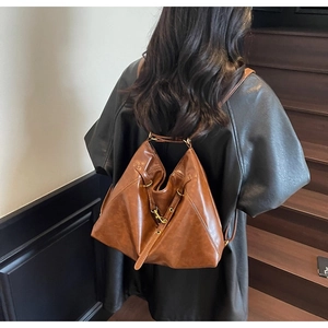 Brown vintage triangle leather backpack with metallic buckle shown in a lifestyle setting