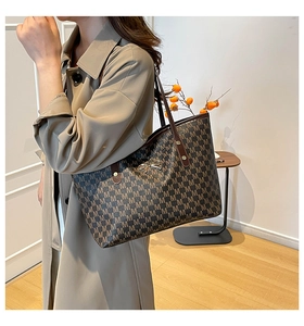Détail du sac cabas marron avec motifs M répétitifs et breloque noeud doré