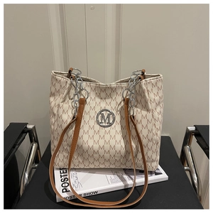 Detail view of canvas tote bag featuring brown M-letter prints and silver metal logo