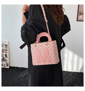 Close-up of pink monogram crossbody bag with M logo pattern and round top handle