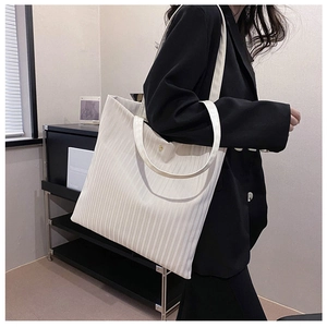 Detail of white corduroy tote bag featuring vertical texture and golden snap button closure