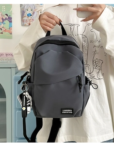 Detail of grey nylon crossbody bag featuring tiered zippers and creative shoe pendant