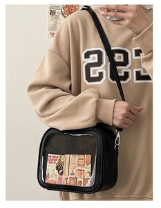 Detail of black ita bag with transparent window showing decorative cards and PU leather texture