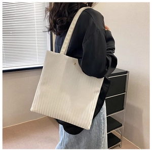 Detailed close-up of white tote bag featuring vertical textured stripes and sturdy straps