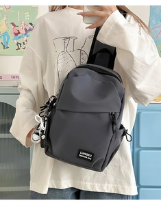 Detail of gray crossbody bag featuring waterproof nylon fabric and a mini shoe charm
