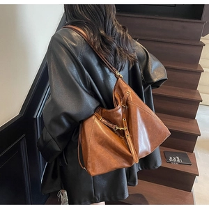 Detailed view of vintage dark brown faux leather texture and metallic buckle on tote bag