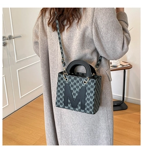 Detail view of the black leather M-letter patch and monograms on a vintage tote bag