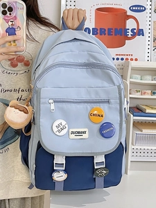 Detail of color-block school backpack with multiple zipper pockets and cute plush charm