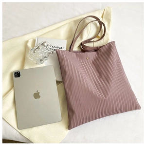 Detail of dusty pink pleated tote bag with golden magnetic snap closure and slim straps