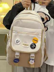 Close-up of color-block backpack with decorative badges and leather brand logo