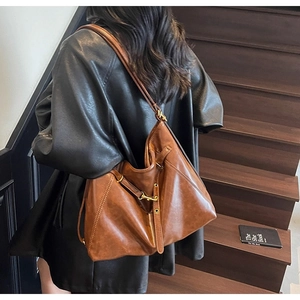 Detail of vintage brown leather hobo bag with metal hooks and drawstring accents