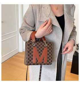 Detail of vintage brown monogram handbag with large leather M applique and gold hardware