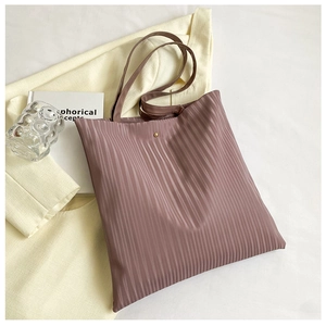 Detail of mauve pleated tote bag texture with minimalist metallic snap button and slim handles
