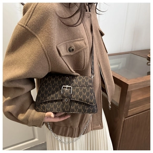 Close-up of vintage brown crossbody bag with M-letter pattern and silver buckle detail